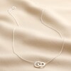 Interlocking Pearl and Crystal Hoops Necklace in Silver laid out on top of beige coloured fabric