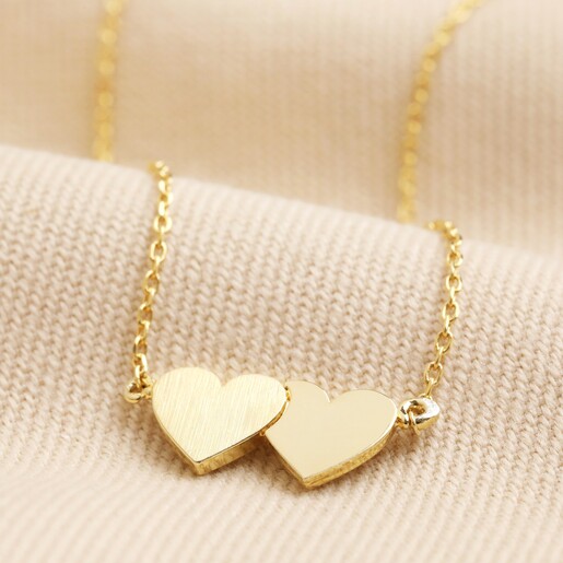 Linked Hearts Pendant Necklace in Gold Close Up of Linked Hearts Pendant Necklace in Gold on Beige Fabric