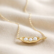 Pearl Three Peas in a Pod Pendant Necklace in Gold on Beige Fabric