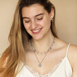 Model smiling looking down wearing Personalised Stainless Steel Zodiac Pendant Necklace against neutral backdrop