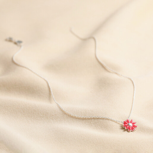 Pink Enamel Daisy Pendant Necklace in Silver laid out over beige coloured fabric