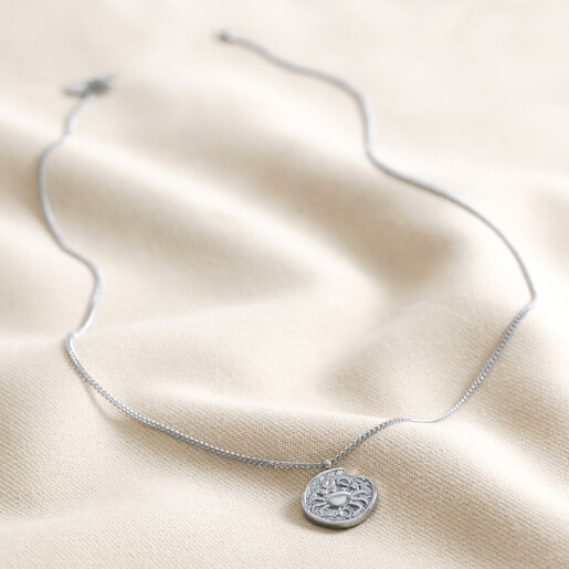 Full Chain of Stainless Steel Cancer Pendant Necklace on beige fabric