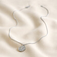Full length Stainless Steel Sagittarius Pendant Necklace lying on beige fabric