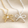 Tiny Pearl Bow Pendant Necklaces in Gold and Silver on Cream Background