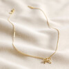 Tiny Pearl Bow Pendant Necklace in Gold on Cream Background