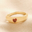 Red Crystal Heart Wide Band Ring in Gold laid on top of beige coloured fabric