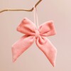 Rose Pink Velvet Bow Hanging Decoration hanging from branch in front of pink background
