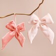 Pink Velvet Bow Hanging Decorations hanging from branch in front of pink background