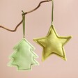 Plush Green Christmas Tree Hanging Decoration and star decoration hanging from branch in front of pink background