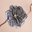 Rounded Grey Velvet Flower Clip decoration on branch in front of pink background