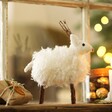 Snowy White Reindeer Ornament in Front of Window with Lights in the Background