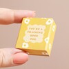 Model holding the Tiny Matchbox Ceramic Egg Token packaging between fingers