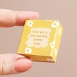 Model holding the Tiny Matchbox Ceramic Egg Token packaging between fingers