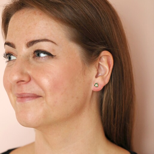 Model looking to side wearing Green Enamel Flower Stud Earrings in Gold in front of neutral coloured backdrop