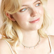 Blonde model looking to side wearing Blue Seed Bead Star and Pearl Charm Necklace in Gold