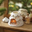 Ceramic Christmas Tree Wax Burner on top of wooden counter with lit tealight inside and matches to the side