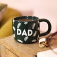 Ceramic Green Leafy Dad Mug on top of wooden counter with pink background