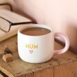 Ceramic Pink Heart Mum Mug in lifestyle shot with tea inside on top of wooden counter book in background