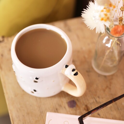 Irregular Ceramic Bee Mug with tea inside on top of wooden counter with vase