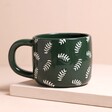 Back of Ceramic Green Leafy Papa Mug in front of neutral coloured backdrop