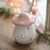 Lifestyle shot of Pink Ceramic Toadstool Wax Burner on top of wooden counter with lit candle in background