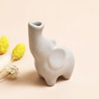 Tiny Elephant Bud Vase with flowers by side on top of beige backdrop