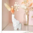 Tiny Elephant Bud Vase on white shelf with flowers inside and vase in background