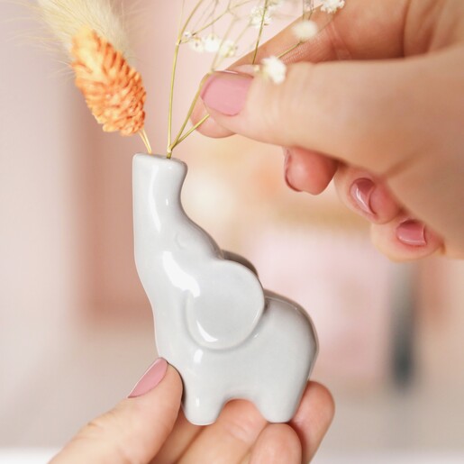 Model placing flowers inside of Tiny Elephant Bud Vase