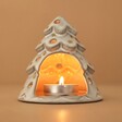 White Ceramic Christmas Tree Tealight Holder with lit tealight inside against neutral backdrop