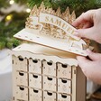 Model placing personalised banner reading Samuel into topper on top of Personalised Wooden Forest Cutout Advent Calendar
