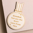 Personalised Wooden Medal Token on plain pink surface