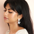 Model looking down wearing Pearlescent Acrylic Flower Drop Earrings against pink coloured backdrop