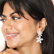 Dark-haired model smiling wearing Pearlescent Acrylic Flower Drop Earrings with hand under chin