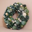 Wooden Green Pinecone Wreath Against Beige Wall