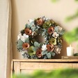 Wooden Pink and Green Blooms Wreath on top of wooden counter in front of beige backdrop
