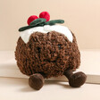 Jellycat Amuseable Christmas Pudding Soft Toy sat on raised surface with neutral background