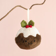 Jellycat Plush Festive Folly Christmas Pudding Decoration hanging from tree branch against neutral coloured background
