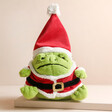 Jellycat Santa Ricky Rain Frog Soft Toy on top of raised surface with neutral coloured backdrop