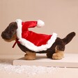 Side of Jellycat Winter Warmer Otto Sausage Dog Soft Toy on top of raised surface with fake snow at bottom
