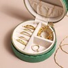 Quilted Velvet Mini Round Travel Jewellery Case in Green Open with Jewellery inside on Beige Background