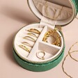 Quilted Velvet Mini Round Travel Jewellery Case in Green Open with Jewellery inside on Beige Background
