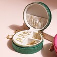 Personalised Quilted Velvet Mini Round Travel Jewellery Case in green Filled with Jewellery on Pink Surface