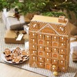 Personalised Wooden Gingerbread House LED Advent Calendar next to christmas tree with gingerbread biscuits next to it