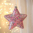 Hanging Pink Glitter LED Star Light Hanging with String Lights in Background 