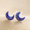 Sterling Silver Blue Glitter Moon Stud Earrings laid out on top of neutral coloured fabric