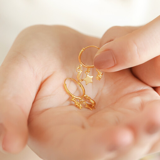 Model Holding Celestial Charm Huggie Hoop Earrings in Gold