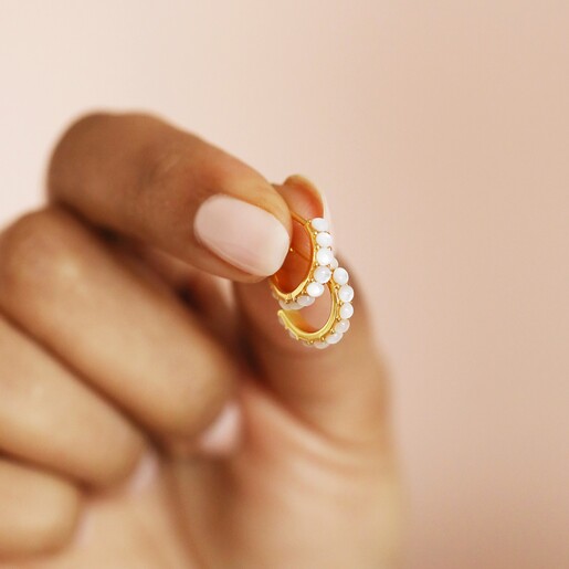 Model Holding Earrings Model Holding Gold Sterling Silver Mother of Pearl Huggie Hoop Earrings Between Fingers