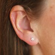 Close up of Sterling Silver Crystal Flower Stud Earrings on dark-haired model
