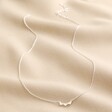 Sterling Silver Tiny Triplet Heart Bar Necklace full length on top of neutral coloured material