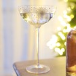 Gold Star Coupe Glass on top of wooden surface with Christmas tree in background